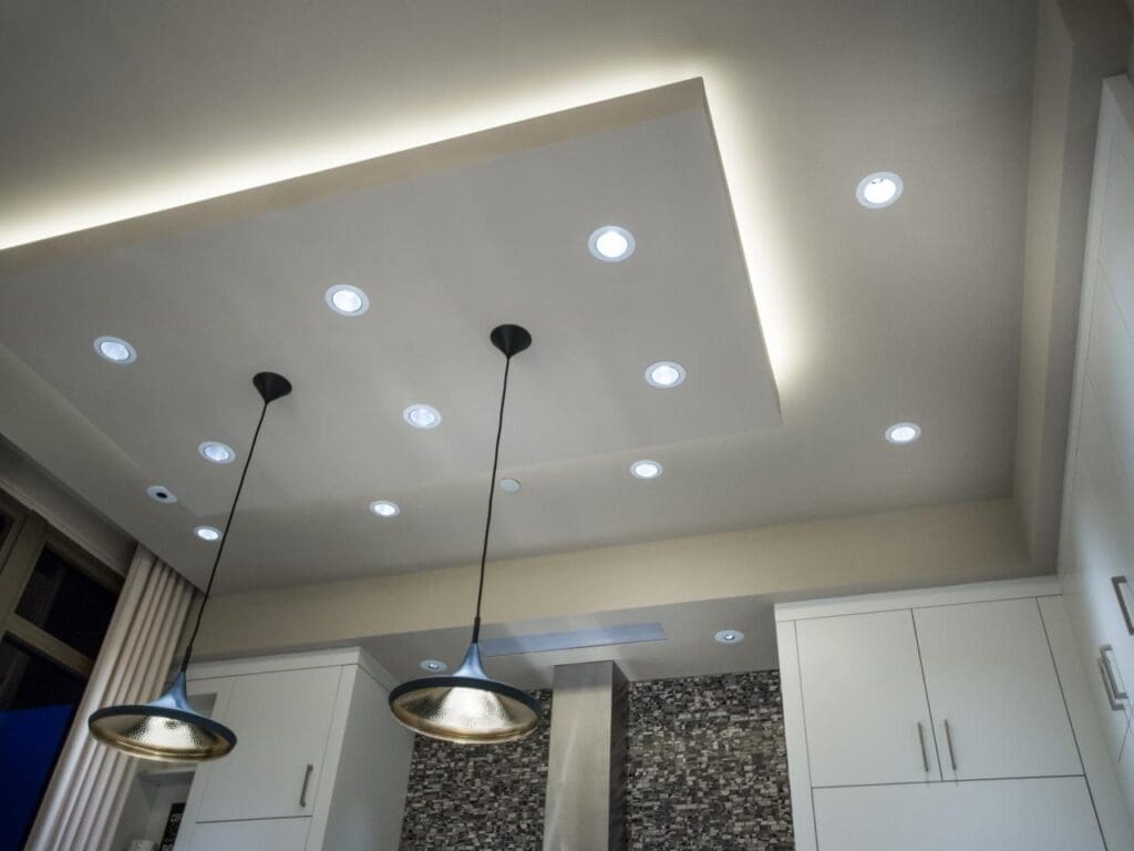 A kitchen with lights on the ceiling and cabinets