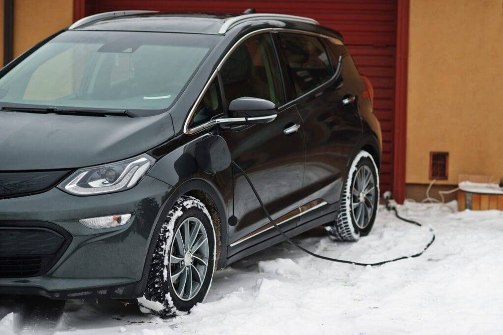 A black car parked in the snow with its door open.