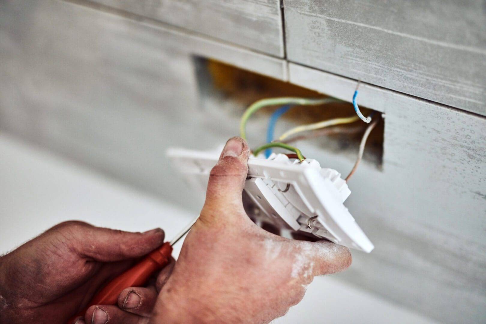 A person is working on an electrical outlet.