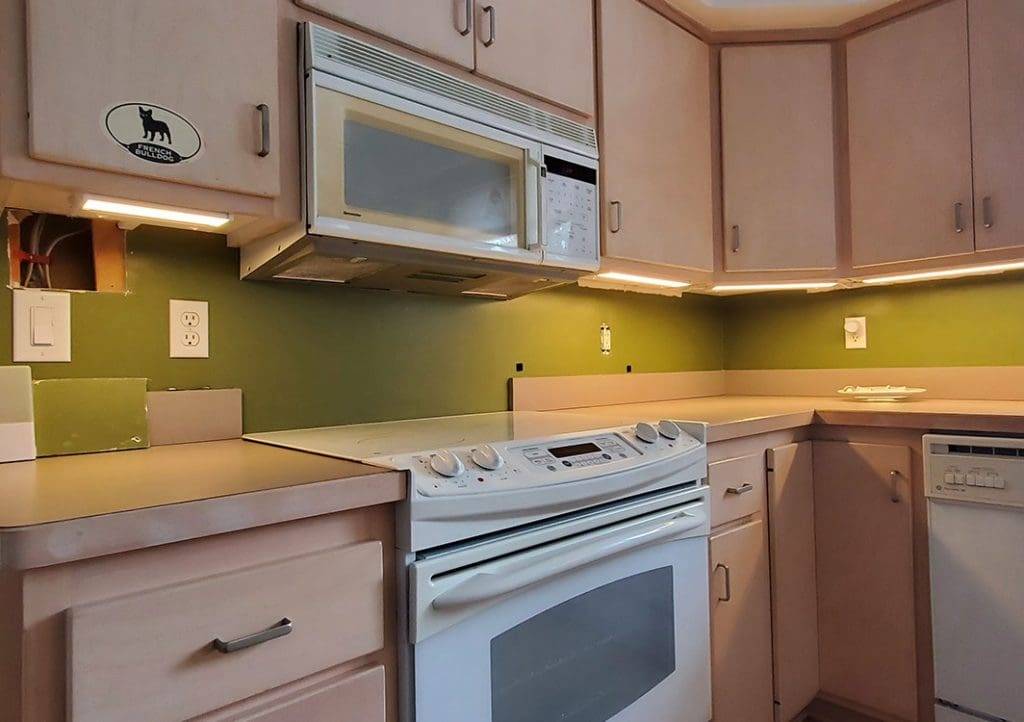 A kitchen with white appliances and green walls.