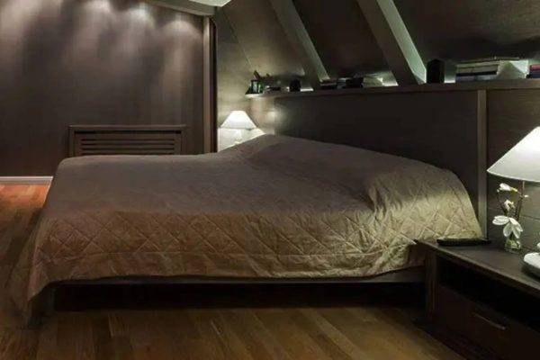 A bed room with a neatly made bed and some lights