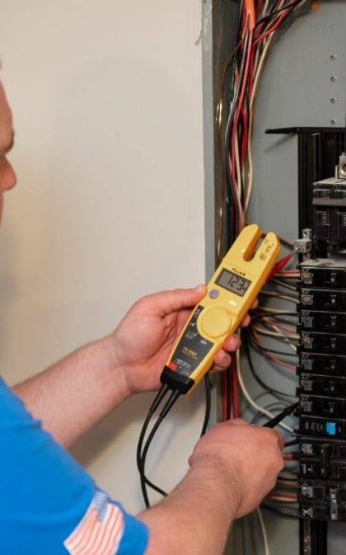 A man is working on an electrical panel.