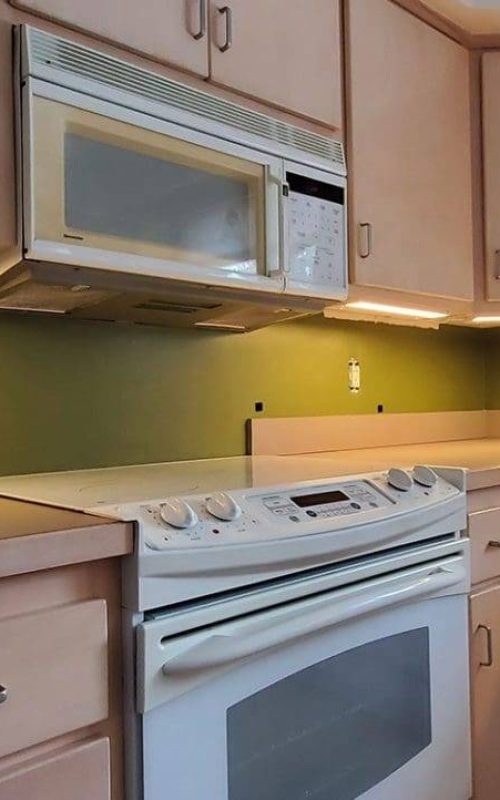 A kitchen with white appliances and green walls.
