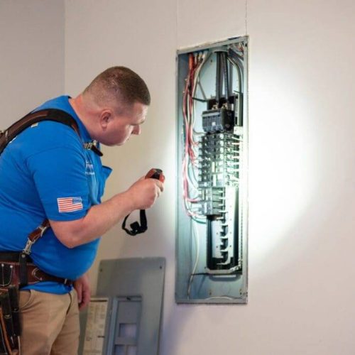 A man is fixing the wires in an electrical box.