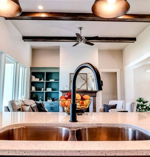 A kitchen sink with a black faucet and white counter.